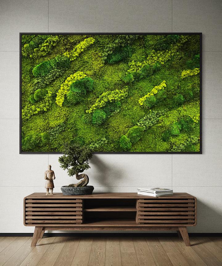 Moss wall art on a gray wall above a wooden console table with decor items.